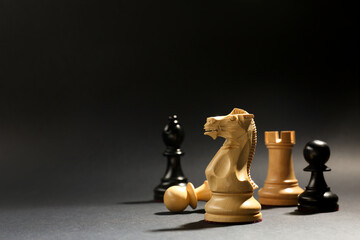 Different chess pieces against dark background, focus on white knight. Space for text