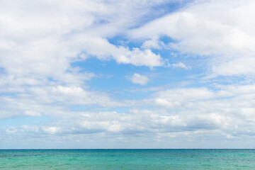 View of the cloudy sky and a strip of turquoise sea. Sea horizon. The horizon where the cloud sky meet the water.