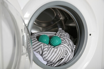 Green dryer balls and clothes in washing machine drum