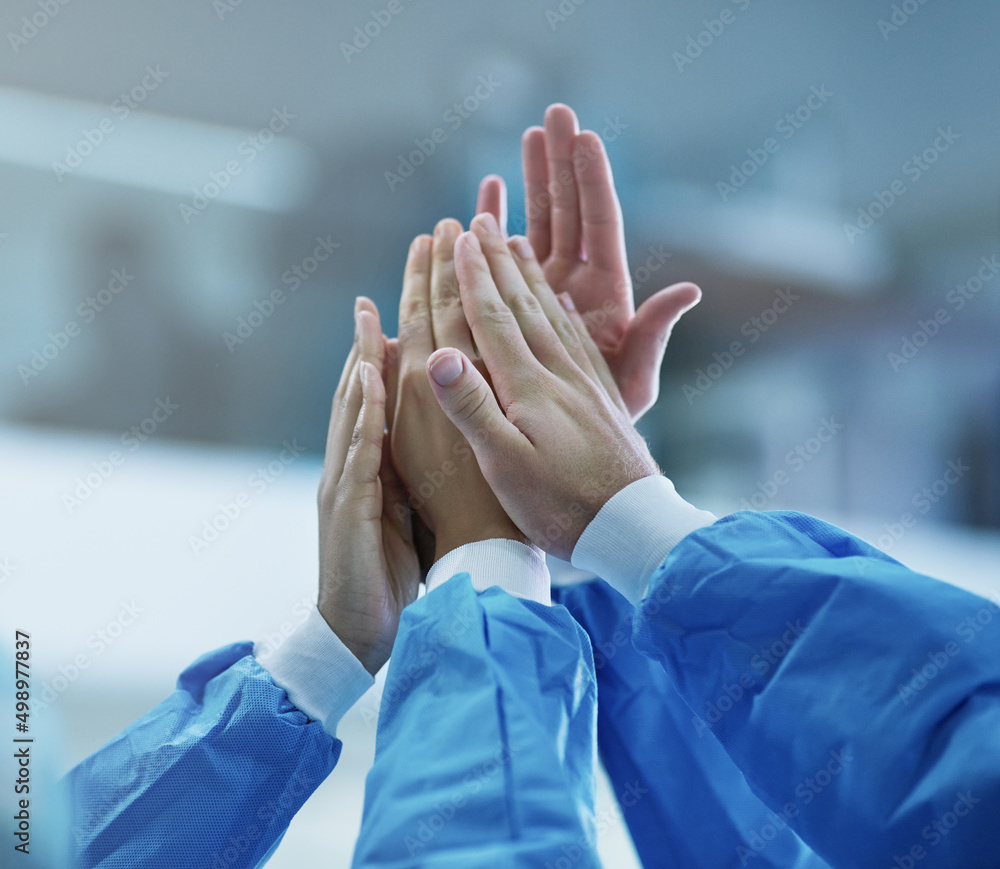 Poster cooperation for a successful operation. cropped shot of a team of surgeons giving each other a high 