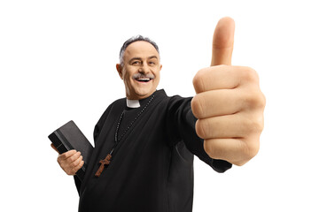 Cheerful catholic priest gesturing thumbs up and holding a bible