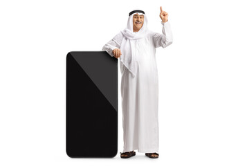 Mature arab man leaning on a big mobile phone and pointing up