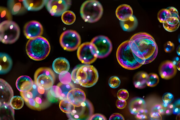 Floating colorful bubbles isolated on black background with iridescent reflections. Blowing soap bubbles is a popular kids enjoyment for parties or fun fairs and a symbol of grace and fragility. 