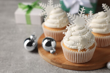 Tasty Christmas cupcakes with snowflakes on grey table. Space for text