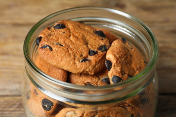 Delicious chocolate chip cookies in glass jar on table, closeup