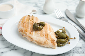 Delicious cooked chicken fillet with capers served on white marble table, closeup
