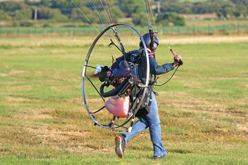 Paramotor pilot taking off from a field	