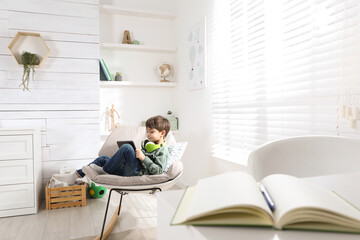 Obraz premium Cute little boy with modern tablet studying online at home. E-learning
