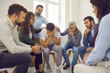 People comforting a grieving crying man. Concerned understanding patients in group therapy...