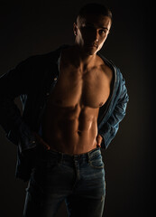 Naklejka na ściany i meble Posing with open shirt in studio while looking at the camera, close up