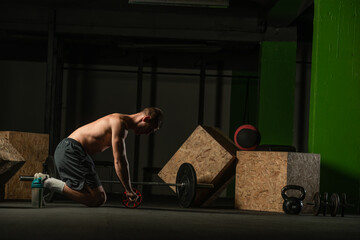 Shirtless pro athlete doing russian twist abs workout. Close up photo of a fit male athlete doing indoor training.