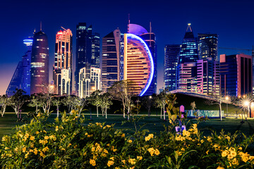 Night view in the city center of Doha, Qatar with many modern luxury buildings and skyscrapers illuminated with numerous lights.