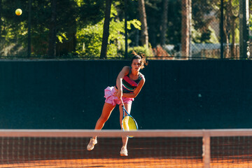 Obraz premium Professional equipped female tennis player serving the tennis ball on a sunny day