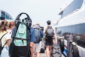Traveler man with diving fins and travel bag walking the boat, from the port, traveland vacation...