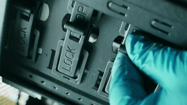 A blue gloved hand closes the switches from the Open to the Lock position. The master closes the electronic locks. Part of electronic equipment. Computer server room. Plastic and metal. Close-up