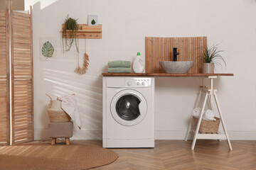 Laundry room interior with modern washing machine and stylish vessel sink on wooden countertop - obrazy, fototapety, plakaty