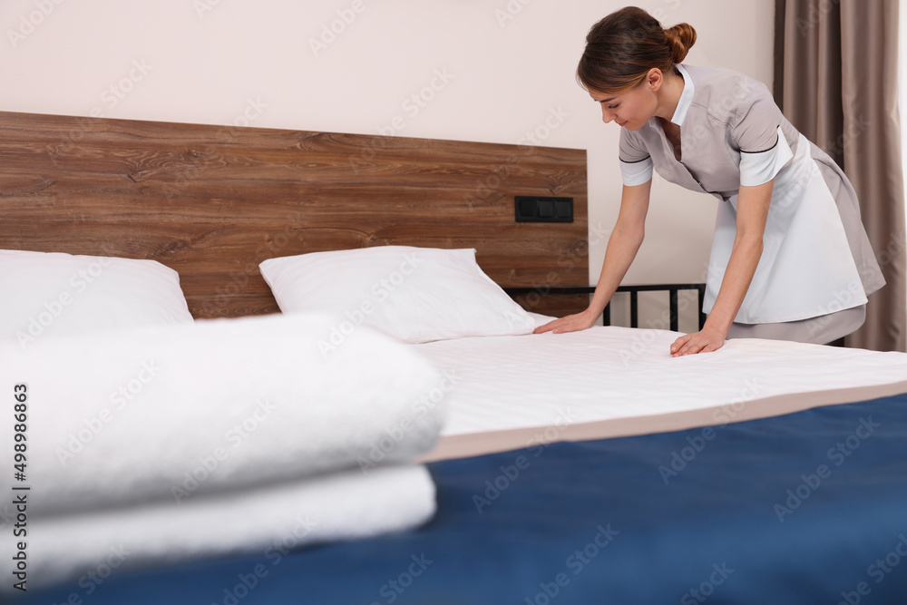 Sticker beautiful chambermaid making bed in hotel room