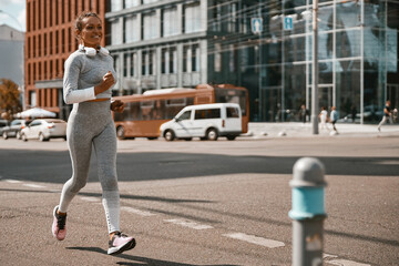Fototapeta na wymiar Fit woman with a mask running along the city street. Healthy lifestyle, Covid 19. Full length