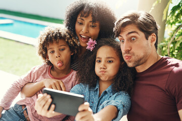 The F in family stands for fun. Shot of a beautiful young family taking a selfie together outdoors.