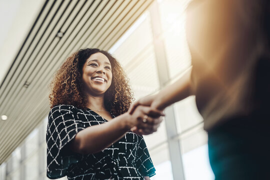 Welcome to the company. Low angle shot of an attractive young businesswoman shaking hands with an associate in a modern workplace.