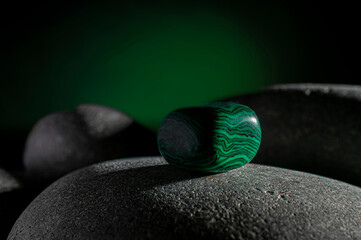 Malachite stone on a rock in the dark with a green light in the background, horizontal Macro...