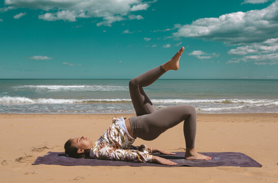 young woman doing pilates exercise on the beach