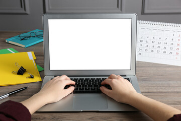 Fototapeta premium Woman using laptop for online studying at wooden table, closeup. Distance learning