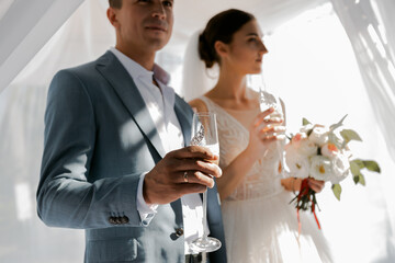The couple is out of focus. Loving wedding couple in a white festive gazebo. The bride has a beautiful long veil and black hair. sunny summer day
