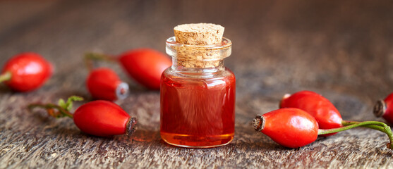 A bottle of rosehip seed oil with fresh rose hips