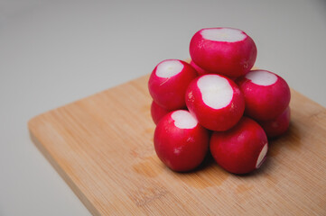 several bright fresh bunch of radishes lies on a wooden board on the table