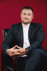 Happy divorced man touching the ring on the ring finger of his right hand Portrait of a handsome man in an elegant suit on a red background. Studio shot.
