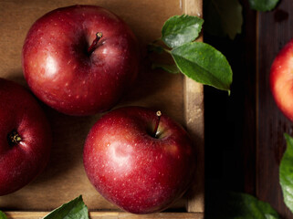 Ripe red apples in wooden box. Top view with space for your text. Ripe red apples in a wooden box. Top view with space for text. Apples whole and cut in half, apple leaves. Harvest from the garden.