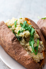 Baked in skin sweet potato with quinoa and lettuce close-up on a plate, vegetarian food