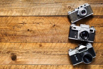 Old retro cameras on vintage wooden boards abstract background.
