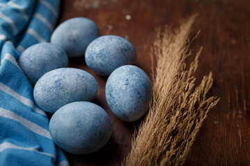 Blue painted easter eggs, some blue striped fabric on brown wooden rustic table background. Close up shot