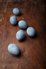 Blue diy painted easter eggs on brown wooden rustic table background. Vertical shot