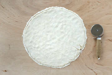 Pizza dough on wooden background, top view