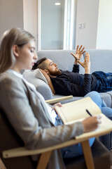 Young man talking to female psychologist during session.