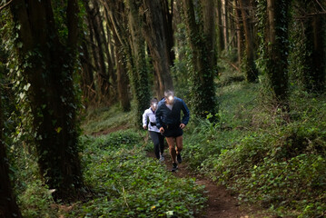 Active man and woman jogging in forest. Two sporty people in sportive clothes exercising outdoors at dusk. Sport, hobby concept © KAMPUS