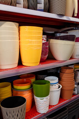 Different plastic flower pots on supermarket shelf. Row of flowerpots in shop or agricultural store.