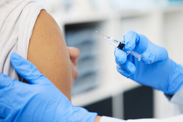 Another life saved. Cropped shot of an unrecognizable doctor injecting her patient with the Covid vaccine in her clinic.