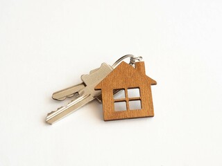 The concept of mortgage lending for the purchase of new housing. Keys with a wooden keychain small house on a white background. Place for text