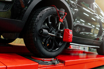 Car mechanic installing wheel alignment sensors, car suspension adjustment. Car mechanic at work