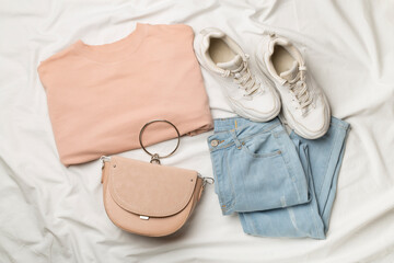 Flat Lay with women casual outfit on white bed sheet, top view
