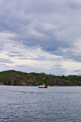 Fototapeta na wymiar Boat passes typical rocky fjord side