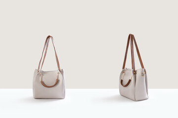 Beautiful beige leather female fashion bag isolated on light beige background, front view
