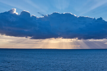 Fototapeta na wymiar sunset beams surround huge cloud over north sea