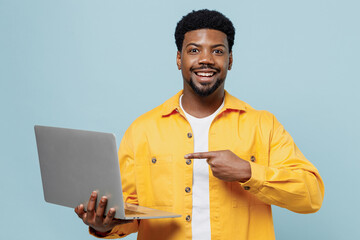 Young surprised amazed happy man of African American ethnicity wear yellow shirt hold use work...