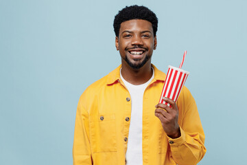 Young smilig happy fun man of African American ethnicity 20s wear yellow shirt hold cup of soda pop...