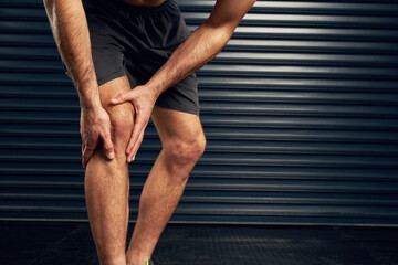 No pain, no gain. Studio shot of an unrecognizable holding his knee against a dark background.